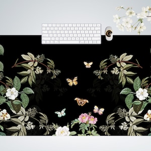 May include: Black and white floral design mouse mat with butterflies and flowers. The mouse mat has a black background with white flowers and green leaves. There are butterflies in various colours flying around the flowers.
