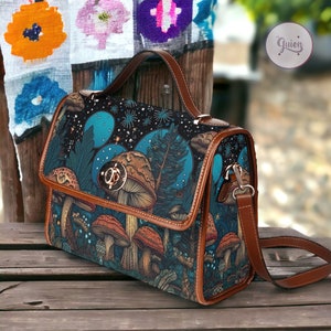 May include: A brown leather satchel with a blue and green fabric lining featuring a mushroom and forest design. The bag has a top handle and a long adjustable shoulder strap.