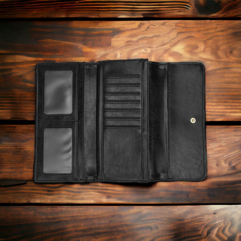 May include: A black leather wallet with multiple card slots and a billfold. The wallet is open and laid flat on a wooden surface.