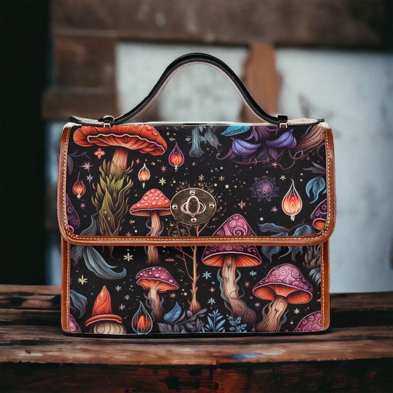 May include: A brown leather satchel with a top handle and a mushroom and floral pattern. The bag has a silver clasp and a black background.
