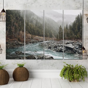 May include: A multi-panel canvas print featuring a misty forest scene with a river flowing through it. The river is a light blue color and the forest is a dark green color. The canvas is mounted on a white wall.