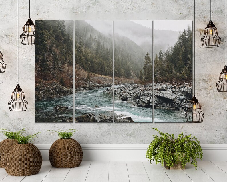 May include: A multi-panel canvas print featuring a misty forest scene with a river flowing through it. The river is a light blue color and the forest is a dark green color. The canvas is mounted on a white wall.