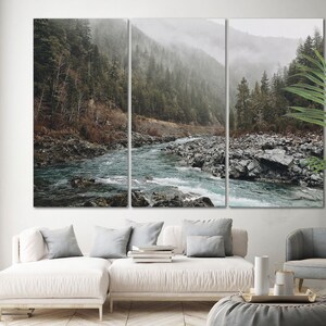May include: A misty forest scene with a river flowing through it. The river is surrounded by rocks and trees. The scene is captured in a three-panel canvas print.