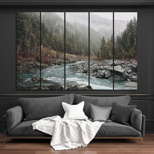May include: A panoramic photograph of a river flowing through a lush green forest. The river is surrounded by rocks and the forest is covered in mist. The photograph is split into five panels.