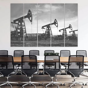 May include: A black and white photograph of four oil derricks pumping oil in a field. The derricks are silhouetted against a cloudy sky.