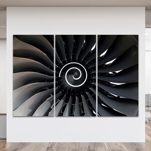 Pode incluir: Impressão em tela de três painéis com um close-up de uma turbina de motor a jato. A imagem mostra o design detalhado das lâminas em tons de cinza e preto, com uma espiral branca no centro. A obra de arte é exibida em um ambiente de escritório moderno.