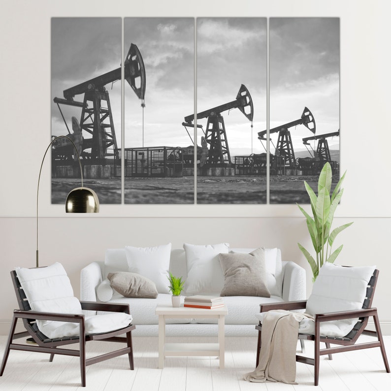 May include: A black and white photograph of three oil derricks pumping oil in a field. The derricks are silhouetted against a cloudy sky.