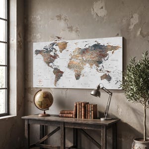 May include: A rectangular wall art piece featuring a detailed world map with a distressed, multi-colored finish in shades of brown, blue, and grey against a white background. The map includes a compass rose in the bottom left corner.