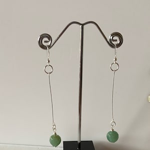 Puede incluir: Un par de pendientes de plata con cuentas de piedras preciosas verdes.