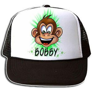 May include: A white and black trucker hat with a green and white cartoon monkey face and the name "BOBBY" printed on the front.