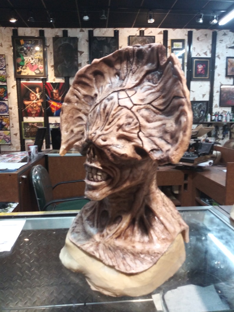 May include: A detailed, brown and beige, sculpted bust of a creature with a large, textured head and a gaping mouth.