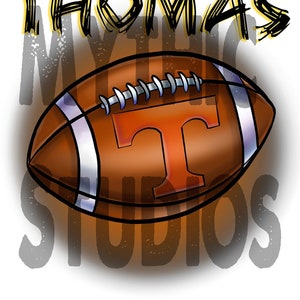 May include: A brown and white football with a large orange "T" on the side. The football is surrounded by the words "THOMAS MYSTIC STUDIOS" in black and yellow.