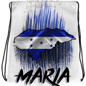 May include: White drawstring bag with a blue and white Honduran flag in the shape of the country. The flag is surrounded by blue and white brushstrokes. The word "MARIA" is written in black at the bottom of the bag.