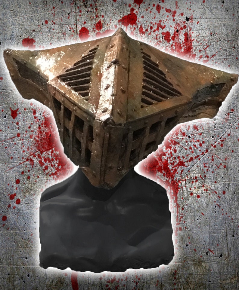 May include: A weathered, cage-like helmet with a rusty brown finish. The helmet features a square design with a slatted front and top, suggesting a medieval or fantasy theme. The background has a grunge texture with red splatter.