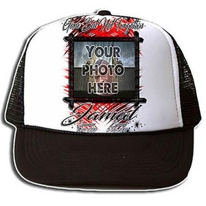 May include: A white and black trucker hat with a red and white design. The hat has a black mesh back and a white front with the text "Gone But Not Forgotten" and "Jamal" in black. There is a rectangular space for a photo with the text "Your Photo Here" in black.