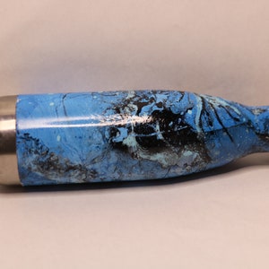 Puede incluir: Una botella de agua de acero inoxidable con un diseño marmoleado azul y negro y una tapa plateada.