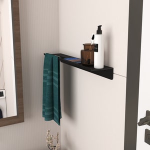 May include: Black metal shelf with a towel hanging on the left side and a bottle of lotion, a small jar, and a toothbrush on the right side.