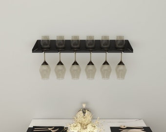 May include: A black metal wine glass rack mounted on a white wall with six clear wine glasses hanging from it.