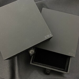 May include: Black jewelry box with a drawer. The box is labeled "IOKA" on the front and the drawer has a black velvet interior.