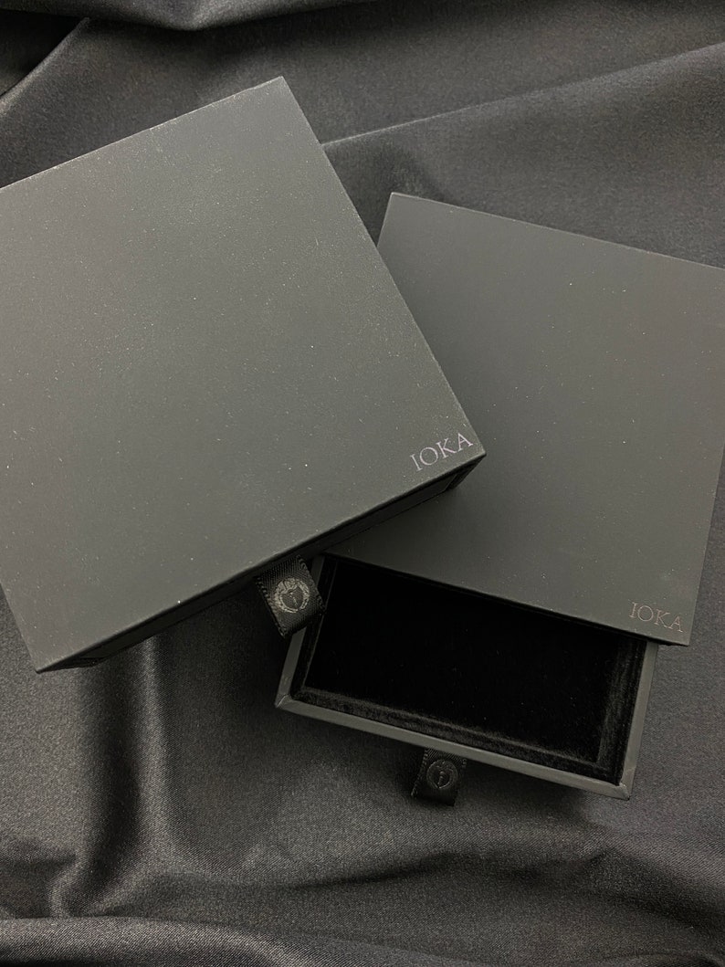 May include: Black jewelry box with a drawer. The box is labeled "IOKA" on the front and the drawer has a black velvet interior.