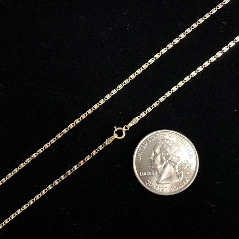 May include: A gold chain necklace with a lobster clasp. The chain is about 18 inches long and is next to a US quarter for size reference.