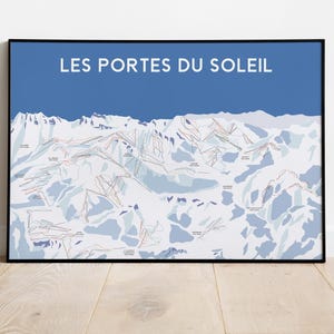 Puede incluir: Impresión enmarcada de un mapa de estaciones de esquí, con el texto "LES PORTES DU SOLEIL" en blanco sobre un fondo azul. El mapa muestra pistas de esquí y terreno montañoso en blanco, gris y rojo. El marco es negro.