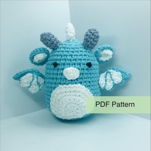May include: A handmade crochet creature in shades of blue, white, and grey. The amigurumi has a round body, wings, and horns. The text "PDF Pattern" is visible on the image.