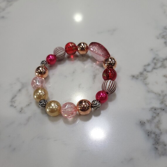 Handmade Stretch band Acrylic Bead Bracelet. Bracelet of red, gold, pearl red, zebra beads with rose spacers. Accessorize in style.