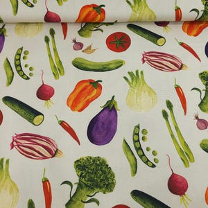 Op de afbeelding: Witte stof met een aquarelpatroon van diverse groenten. Het ontwerp bevat tomaten, courgettes, rode paprika's, aubergines, broccoli, asperges en rode uien. De groenten zijn in tinten rood, groen, oranje en paars.