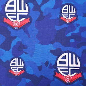 Può includere: Tessuto mimetico blu con un motivo ripetuto di uno stemma bianco e nero con le lettere "BWFC" e l'anno "1877" in rosso.