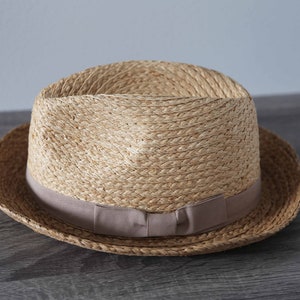 May include: A straw hat with a brown woven band and a light brown brim.