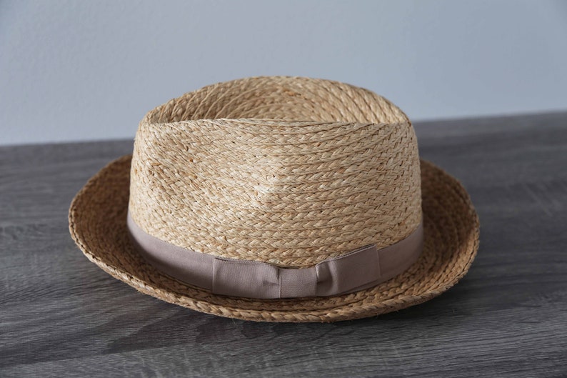 May include: A straw hat with a brown woven band and a light brown brim.