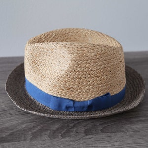 May include: A straw hat with a blue ribbon around the crown. The hat has a brown band around the brim.