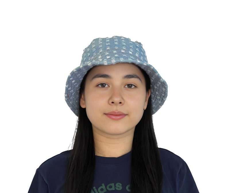 K&ouml;nnte beinhalten: Eine Person tr&auml;gt einen blauen Jeans-Bucket-Hut mit wei&szlig;em Muster. Der Hut hat einen ausgefransten Rand.