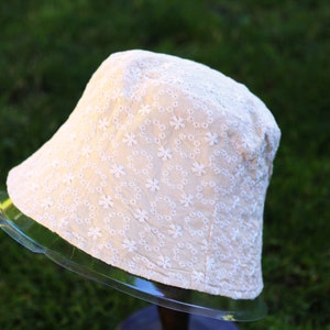 May include: A white bucket hat with a delicate floral embroidery pattern.