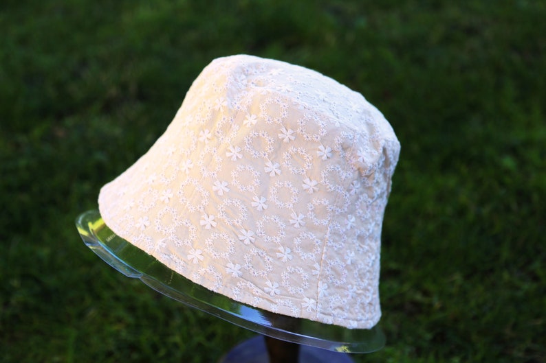 May include: A white bucket hat with a delicate floral embroidery pattern.