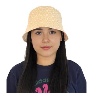 May include: A beige bucket hat with a white floral embroidery pattern. The hat is made of a soft, lightweight fabric and has a wide brim.