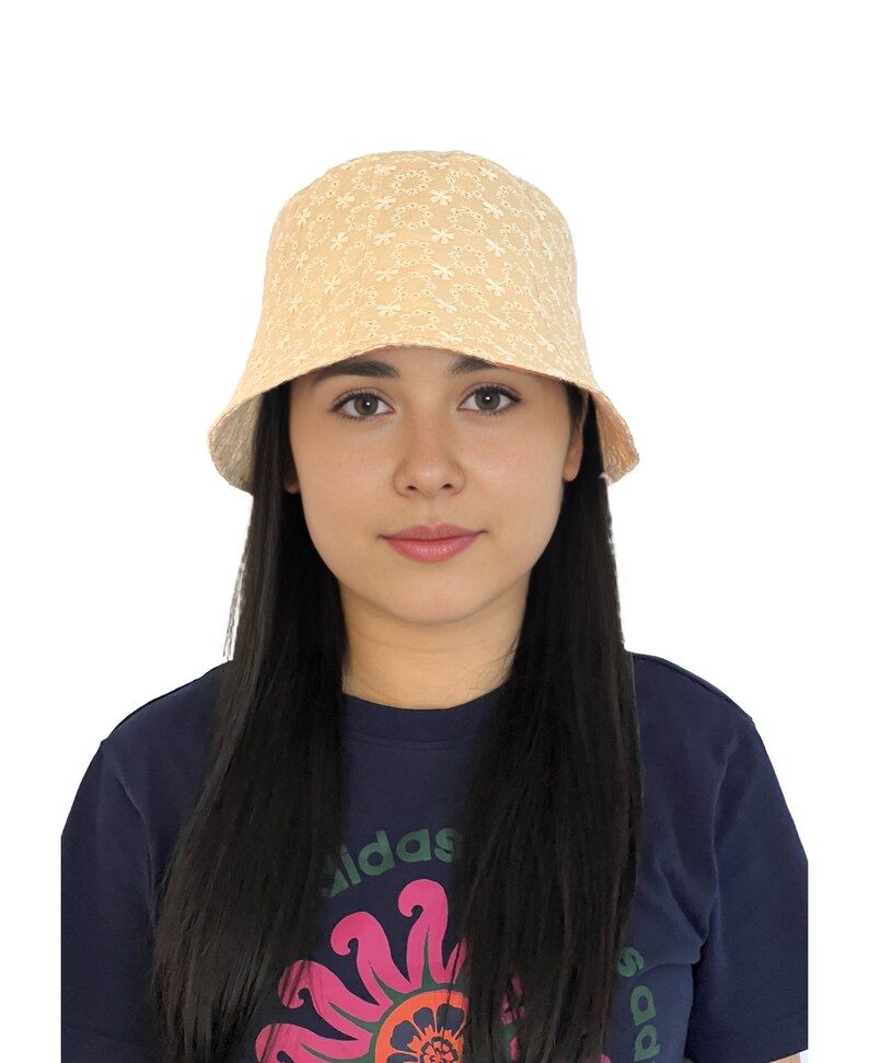 May include: A beige bucket hat with a white floral embroidery pattern. The hat is made of a soft, lightweight fabric and has a wide brim.