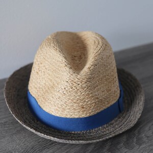 May include: A straw hat with a blue ribbon band. The hat has a wide brim and is made of a natural woven material.