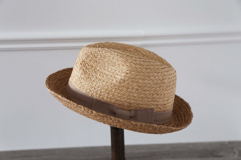 May include: A light brown straw fedora hat with a brown ribbon band.