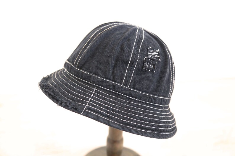 May include: A black denim bucket hat with white stitching and a distressed detail on the crown.