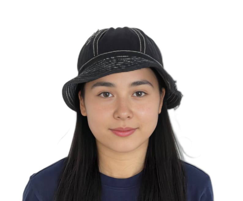 May include: A woman with long black hair is wearing a black bucket hat with white stitching. She is wearing a dark blue shirt.