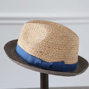 May include: A straw fedora hat with a wide brim and a blue ribbon around the crown.