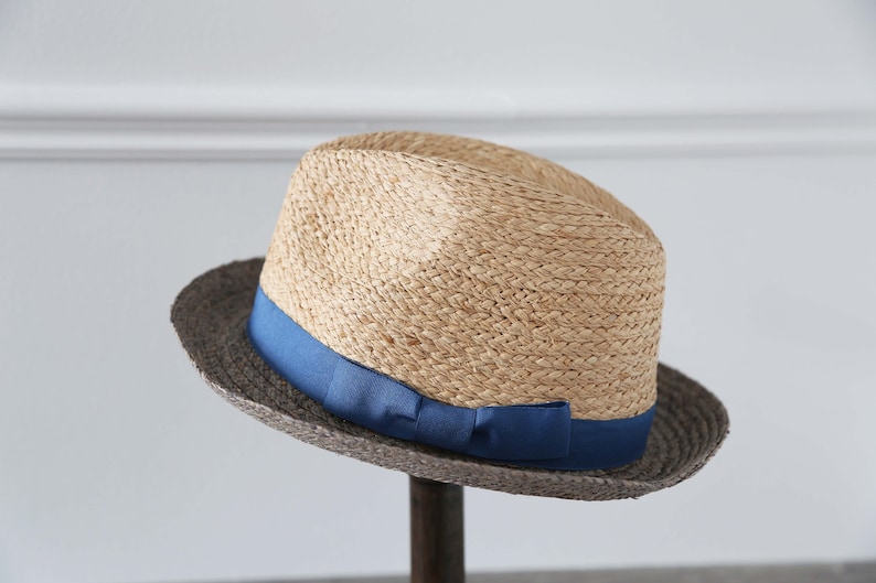 May include: A straw fedora hat with a wide brim and a blue ribbon around the crown.