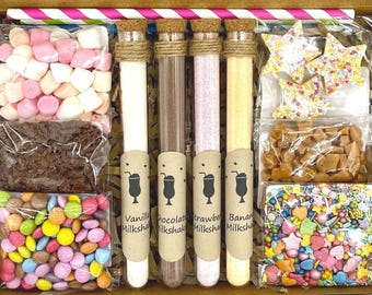 Puede incluir: Una caja de regalo llena de ingredientes para hacer cuatro batidos diferentes: vainilla, chocolate, fresa y plátano. La caja incluye mezclas en polvo, chispas, malvaviscos, chispas de chocolate y caramelos.