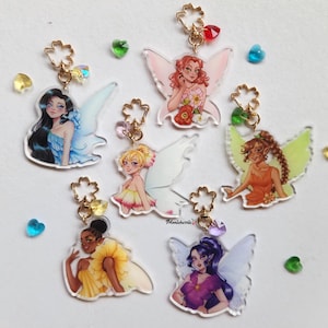 May include: Acrylic fairy charms with gold-colored hardware. Each charm features a different fairy design with colorful wings and outfits. The charms are adorned with iridescent beads and small, heart-shaped gems. The charms are on a white background.