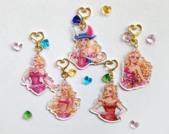 May include: Five colorful keychains featuring different cartoon characters. Each keychain has a gold heart-shaped charm and a clear acrylic charm with a cartoon character. The characters are all female and have blonde hair. The characters are wearing different outfits, including a pink dress, a blue and white dress, a red dress, a white dress, and a pirate outfit.