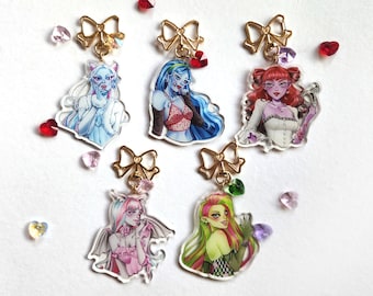 May include: Five colorful character charms with gold bows and clear acrylic backgrounds. The characters are a blue-haired girl, a green-haired girl, a pink-haired girl, a red-haired girl, and a white-haired girl.