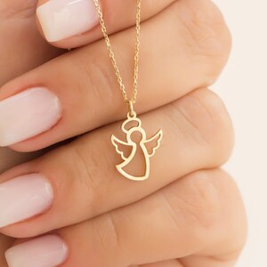 May include: A gold chain necklace with a delicate angel pendant. The angel is outlined in gold and has wings.