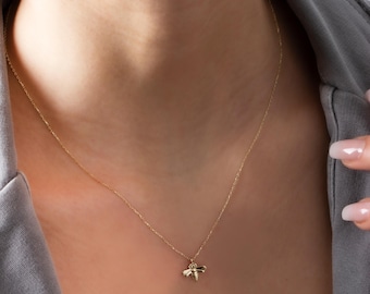 May include: A delicate gold chain necklace with a small bee pendant.